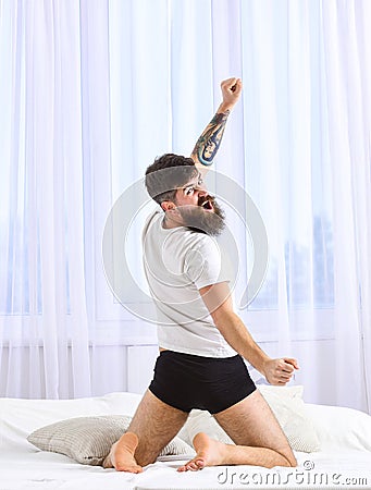 Guy stretching arms, full of energy in morning, rear view. Macho in underpants stretching, looking back and yawning. Man Stock Photo