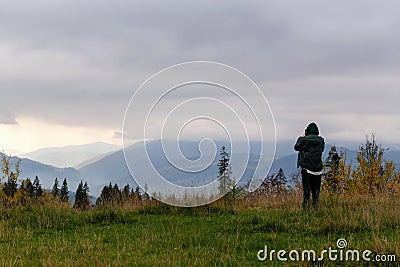 Guy takes pictures of beautiful autumn cloudy mountains on his phone Stock Photo