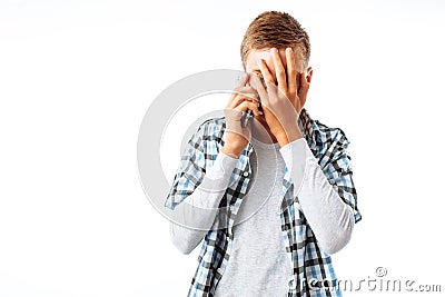 The guy is talking on the phone and shocked by what he hears, covered his face with his hand to hide the shame in the Studio on a Stock Photo