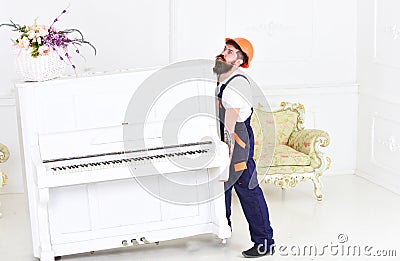 Guy from transportation company moving old piano alone. Tired guy lifting heavy stuff Stock Photo