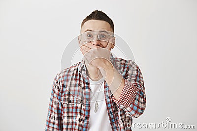 Guy tries to hold laugh on important meeting. Portrait of attractive adult man in glasses chuckling and covering mouth Stock Photo