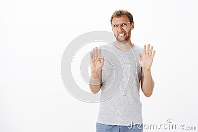 Guy trying refuse proposal being not in mood raising palms in rejection gesture clenching teeth and making sorry Stock Photo