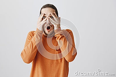 Guy wants to pull out his eyes from shock. Portrait of handsome surprised boyfriend in orange sweater covering vision Stock Photo