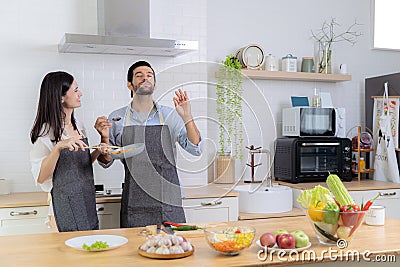 The guy was very happy tasting his girlfriend's cooking skills. A young couple in love having fun Stock Photo