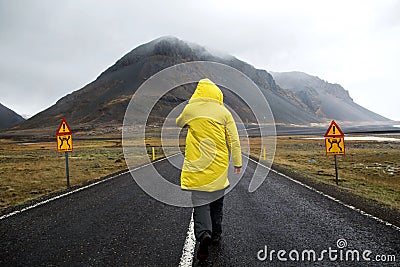 guy in a yellow cloak is walking down the road in the mountains, a tourist. The concept of freedom. Stock Photo