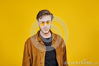 guy with yellow sunglasses posing on a yellow background Stock Photo