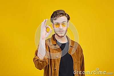 guy with yellow sunglasses posing on a yellow background Stock Photo