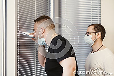 Hipsters businessman peeking through blinds in office Stock Photo