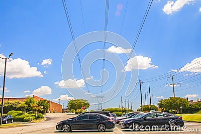 Large industrial power poles and lines with a cloudy blue sky over cars Editorial Stock Photo