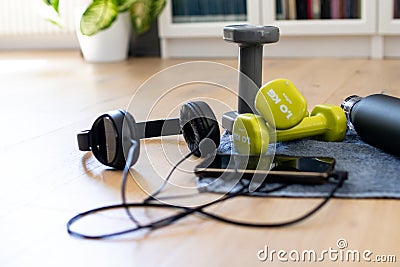 Gym at home, accessories for fitness at home. Tools for sport activities: towel, headphone, mobile phone, dumbbell and water tank Stock Photo