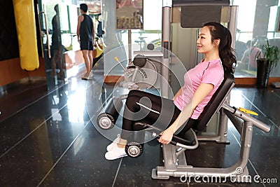 Gym leg extension exercise workout woman indoor. Beautiful, press. Stock Photo