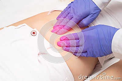 A gynecologist doctor probes the lower abdomen of a girl who has pain and inflammation of the reproductive system. Ovarian cyst, Stock Photo