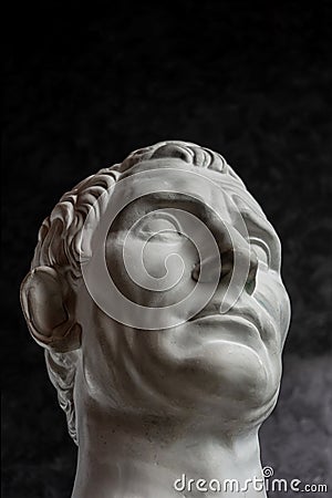 Gypsum copy of ancient statue Augustus head on dark textured background. Plaster sculpture man face. Stock Photo