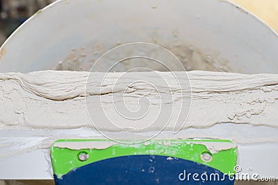 Gypsum plaster on a long spatula on a bucket Stock Photo