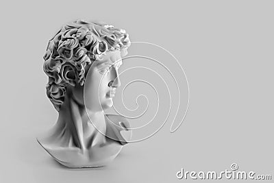 Gypsum statue of David`s head. Michelangelo`s David statue plaster copy on grey background with copyspace for text. Ancient gree Editorial Stock Photo
