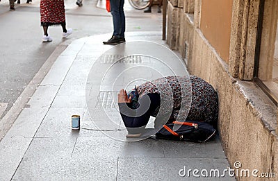 gypsy woman asking for alms kneeling on the ground with her hand Editorial Stock Photo