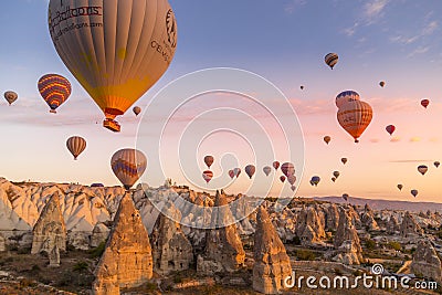 GÃ¶reme, Cappadocia, Turkey - October 7 2019: Hot air balloons filled with tourists during a pink sunrise floating along valleys Editorial Stock Photo