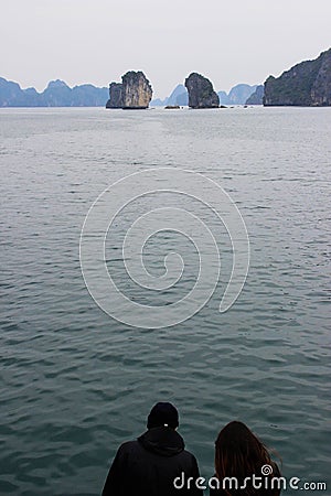 The guy and the girl are sitting together against the backdrop of the cliffs of the Ha Long Bay in Vietnam Editorial Stock Photo