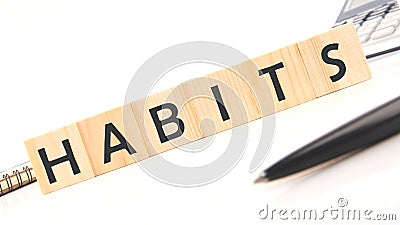 HABITS word assembled from wooden cubes next to a calculator, pen and notepad Stock Photo