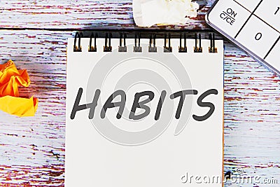 HABITS word written on a sheet of notebook lying on old vintage boards with a calculator and folded paper Stock Photo