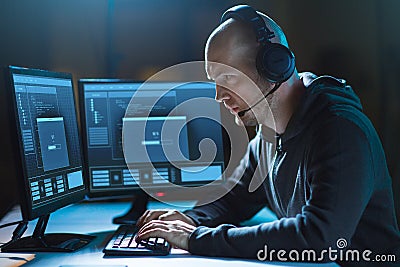 Hacker with computer and headset in dark room Stock Photo