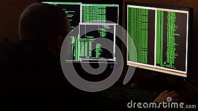 Hacker in glasses breaking code. Criminal hacker penetrating network system from his dark hacker room. Computer program Stock Photo
