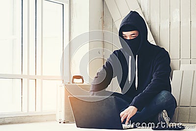 Hacker holding gun working on his computer, war, terrorism , terrorist and bandit concept. Glitch effect and copy space. Black ma Stock Photo