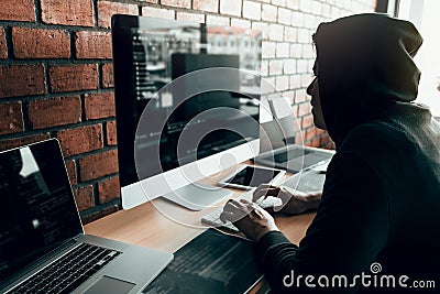 Hacker in the hood working with computer with hacking breaking into data servers Stock Photo