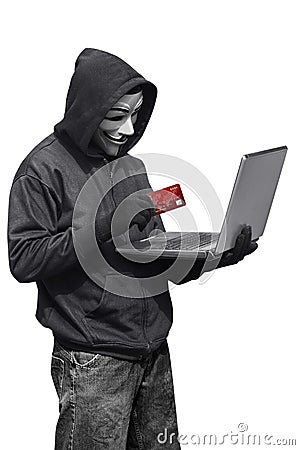 Hacker man wearing anonymous mask holding laptop and credit card Editorial Stock Photo