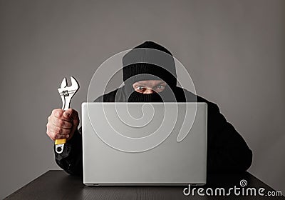 Hacker in mask using a laptop Stock Photo