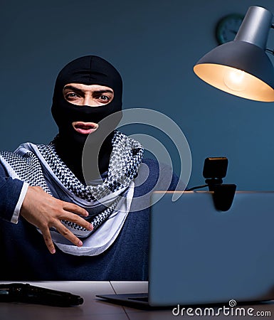 Hacker wearing balaclava mask hacking computer Stock Photo