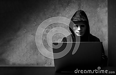 Hacker wearing a white mask in front of his computer. hacker hacks network Stock Photo