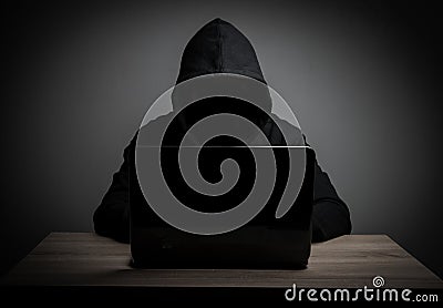 Hacker work front of his laptop computer with dark face. Stock Photo