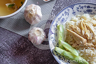 Hainanese chicken rice served in a Chinese style dish with soy sauce and broth on a gray table Stock Photo