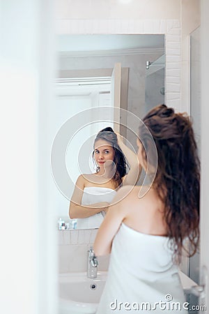 Hair and body care. Woman touching wet hair and smiling while looking in the mirror. Portrait of girl in bathroom applying condit Stock Photo