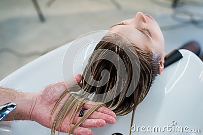 Hair care in modern spa salon. Male hairdresser washing teen girl's hairs Stock Photo