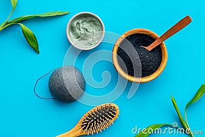 Hair care, hair spa. Cosmetics based on bamboo charcoal powder near comb on blue background top view Stock Photo