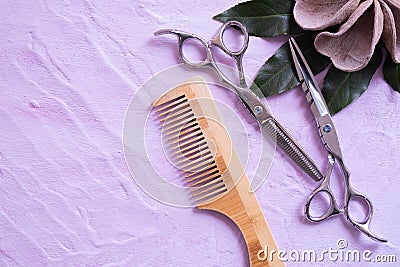 A hair comb, scissors and wood decorations lie on a textured background Stock Photo