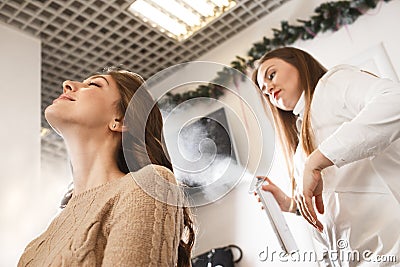 Hair dresser spraying with varnish to client`s hair style Stock Photo