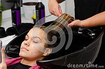 Hair stylist applying hair mask and combing clients wet hair with brush Stock Photo