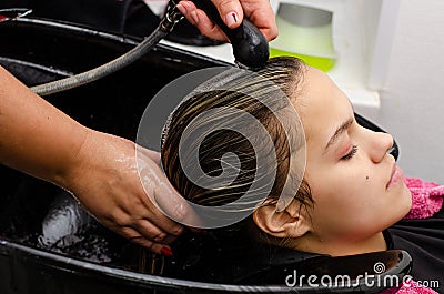 Hair stylist washing hair of a young pretty woman Stock Photo