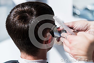 Haircut men barbershop. Barber using grooming professional haircutting machine to make haircut to client close up. Man Stock Photo