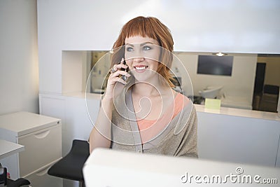 Hairdresser Answering Mobilephone At Reception In Salon Stock Photo