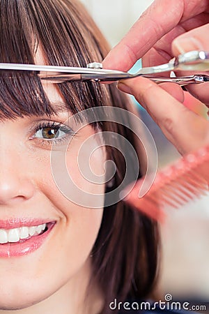 Hairdresser cutting woman bangs hair Stock Photo