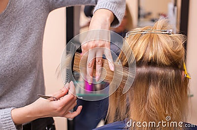 The hairdresser does a haircut with scissors of hair to a young girl, a blonde Stock Photo