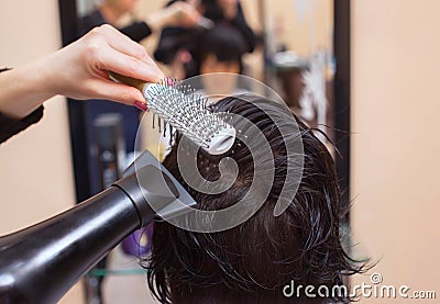 He hairdresser dries her hair a brunette girl Stock Photo