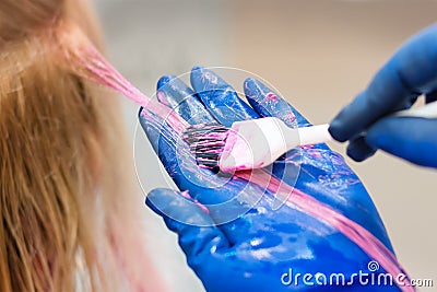 Hairdresser is dying female hair. Hands in glives with brush, coloring in hair salon. Stock Photo