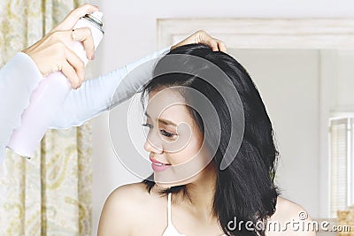 Hairdresser fixing her hair of model with hairspray Stock Photo