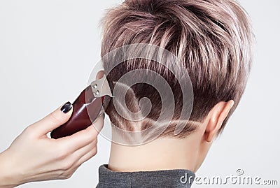Hairdresser makes a creative haircut with a razor to a beautiful woman Stock Photo