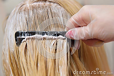 The hairdresser smears the paint on his hair with a comb, for co Stock Photo